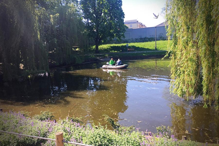 Na zdjęciu widać mężczyzn płynących na łódce w stawie w Parku Traugutta