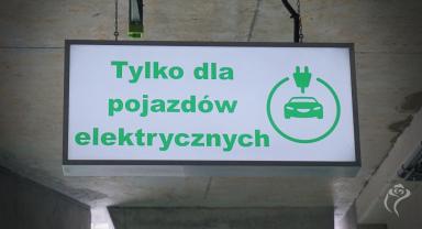 Na zdjęciu widać tablicę informacyjną o miejscu dla pojazdów elektrycznych