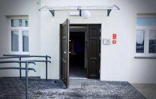 Na zdjęciu widać otwarte drzwi wejściowe do kamienicy