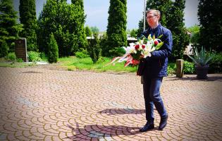 Na zdjęciu widać jedną osobę niosącą kwiaty