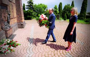 Na zdjęciu widać dwie osoby niosące kwiaty