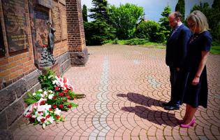 Na zdjęciu widać dwie osoby niosące kwiaty
