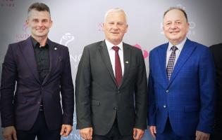 Na zdjęciu widać trzy osoby stojące obok siebie