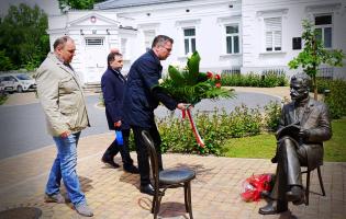Na zdjęciu widać trzy osoby składające kwiaty