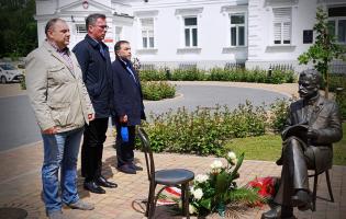 Na zdjęciu widać trzy osoby składające kwiaty