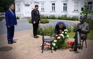 Na zdjęciu widać trzy osoby składające kwiaty