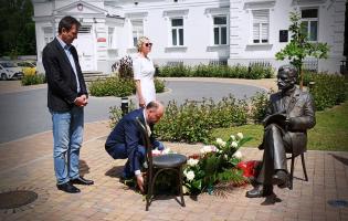 Na zdjęciu widać trzy osoby składające kwiaty