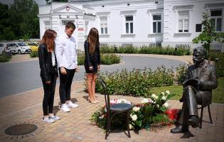 Na zdjęciu widać trzy osoby składające kwiaty