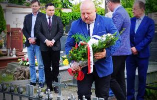 Na zdjęciu widać pięć osób, jedna składa kwiaty