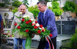 Na zdjęciu widać dwie osoby składające kwiaty
