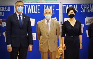 Na zdjęciu widać trzy stojące osoby