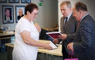 Na zdjęciu widać trzy osoby i moment wręczenia dyplomu
