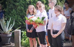 Na zdjęciu widać uczniów czekających na złożenie kwiatów