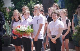 Na zdjęciu widać uczniów czekających na złożenie kwiatów