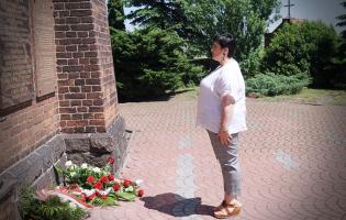 Na zdjęciu widać jedną osobę składającą kwiaty