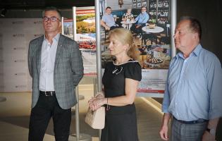 NA zdjęciu widać trzy osoby stojące przy wystawie